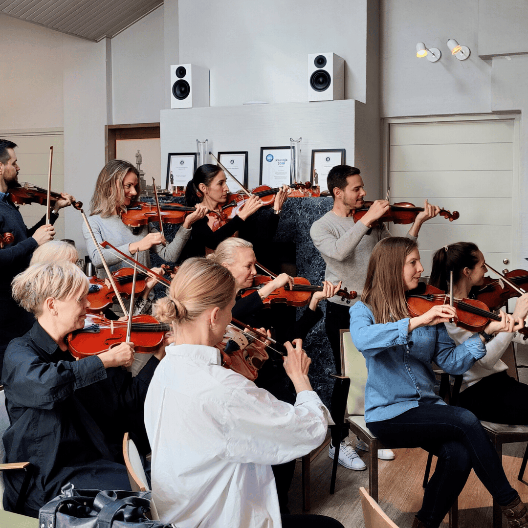 Personer spiller violin sammen under et musikalsk teambuilding arrangement i Kolding.
