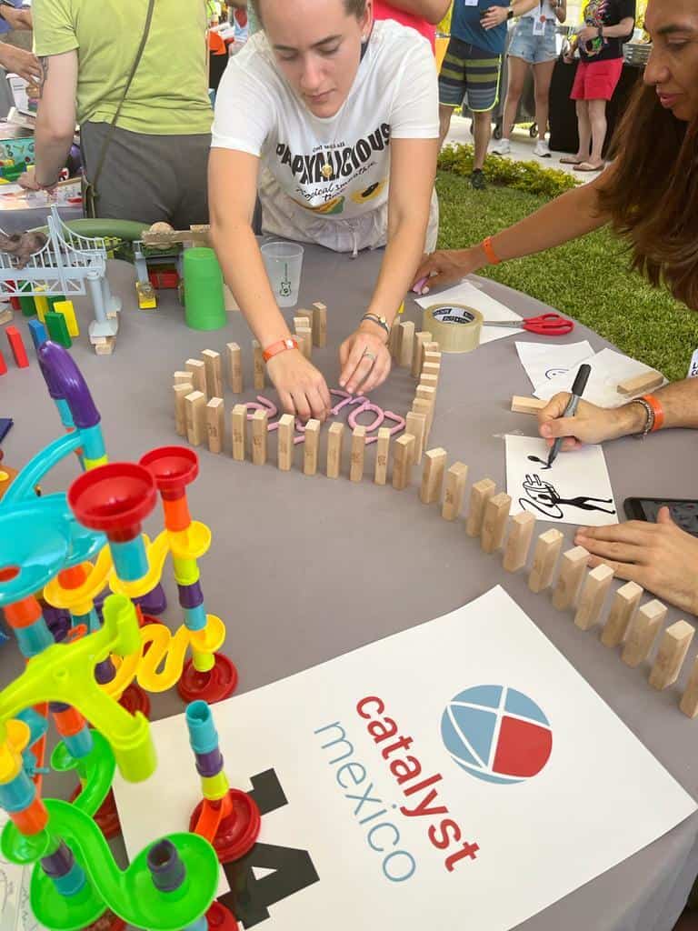 Teambuilding-deltagere bygger en kædereaktion med dominobrikker og koncentreret fokus.